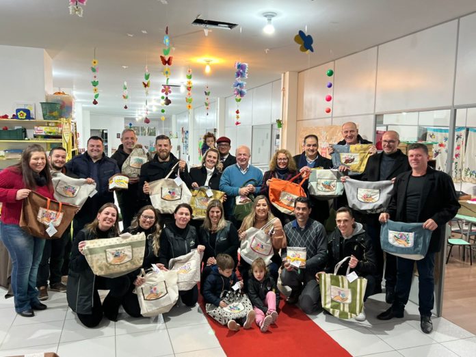 Equipe escolar, executivo e legislativo exibem as sacolas do projeto 