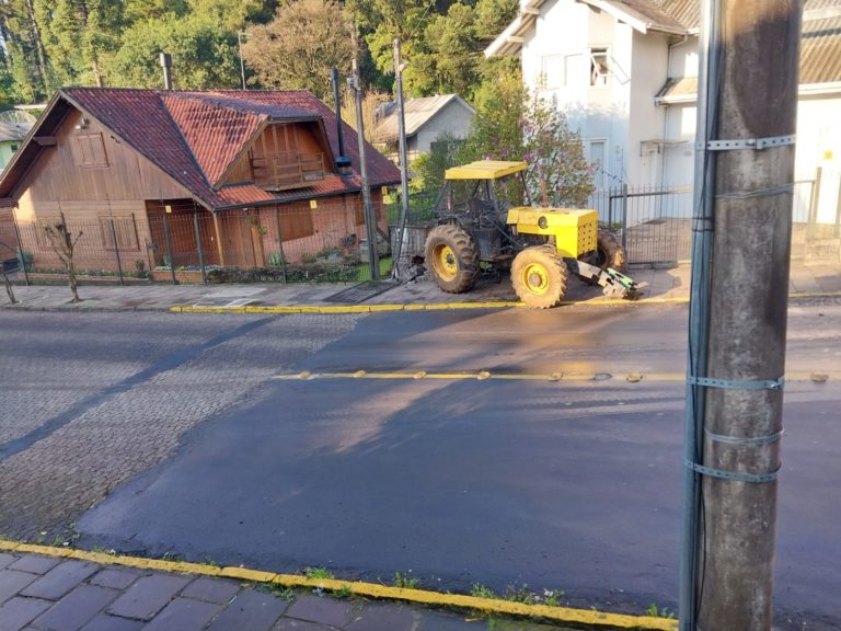 Trator cai de caminhão e bate em muro de uma casa